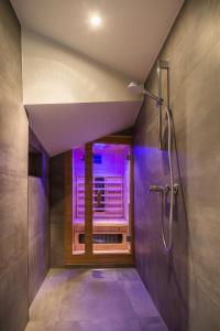 baño con ducha y ventana con luces moradas. en Residence Novak Bohinj en Bohinj