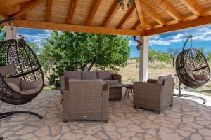 a patio with chairs and swings under a wooden roof at House vacation with pool,near Šibenik in Planjane