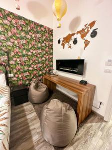 sala de estar con pared de flores, TV y 2 reposapiés en Kofler GuestHouse, en Barletta