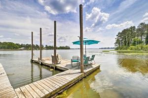 a dock with two chairs and an umbrella on a lake at Home on Jordan Lake with Shared Dock and Boat Slip! in Wetumpka
