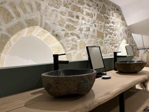 a bathroom with two sinks and a stone wall at Appart Spa Privatif Laon in Laon