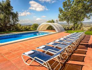 - une rangée de chaises longues à côté de la piscine dans l'établissement Catalunya Casas Country Chateau for 22 persons - close to Sitges!, à Les Masuques