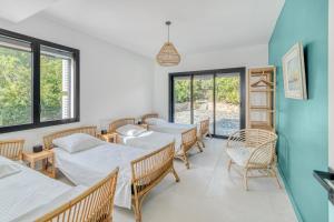 Habitación con 4 camas, sillas y ventanas en Villa 250m 8 adultes 4 enf vue mer, en La Croix-Valmer