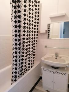 a bathroom with a sink and a shower curtain at Iris, Gîte Saint Antoine, Orcival, entre Sancy et Volcans d'Auvergne in Orcival