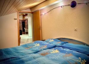 Schlafzimmer mit einem Bett mit blauer Bettwäsche und Beleuchtung in der Unterkunft Haus Antares in Saas-Almagell