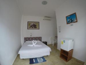 a bedroom with a white bed and a refrigerator at Stefany's Lodging in Puerto Baquerizo Moreno