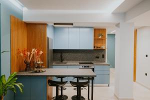 a kitchen with blue cabinets and a island with stools at Azuro Luxury Living in Thessaloniki