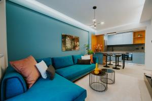 a living room with a blue couch and a kitchen at Azuro Luxury Living in Thessaloniki