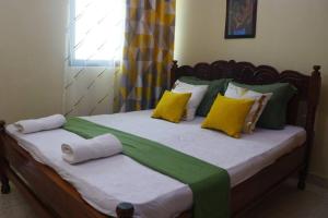 1 dormitorio con 1 cama con almohadas amarillas y verdes en Stylish Cozy Home, en Mombasa
