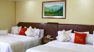 a hotel room with two beds with red and white pillows at Hotel Real del Sur in Mexico City