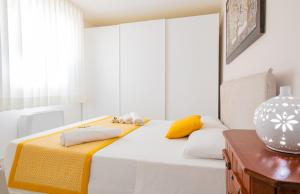 a white bedroom with a bed with yellow and white pillows at Casa D'Amore con Piscina Privata in Alessano
