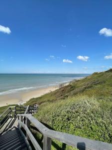 Un escalier en bois mène à une plage donnant sur l'océan. dans l'établissement L'Effet Mer, à Équihen-Plage