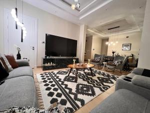 a living room with a couch and a table and a tv at شقة فندقية لاكجري مع بلكونة الملقا in Riyadh