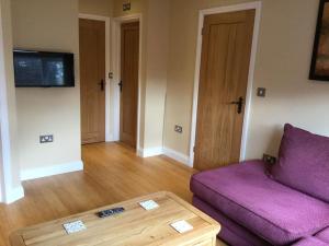 a living room with a purple couch and a table at Beautifully appointed & cosy self contained annexe 