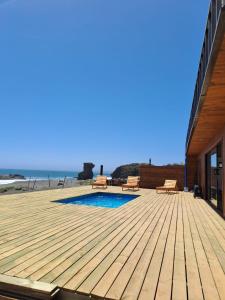 una terrazza in legno con piscina e spiaggia di Casa MORENA by Alto Curanipe a Pelluhue