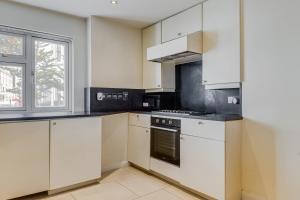 a kitchen with white cabinets and a stove at Care Property London- Apartments in London