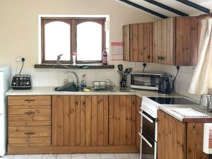 una cocina con armarios de madera y fregadero en Elm Barn View, en Freethorpe