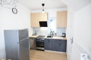 a kitchen with a stainless steel refrigerator and wooden cabinets at Domki U Zbyszka nad jeziorem z balią ogrodową! in Kiedrowice +5 photos