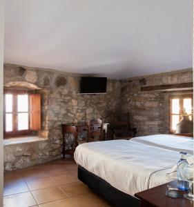 a bedroom with a large bed in a stone wall at Tugasa Hotel La Posada in Villaluenga del Rosario