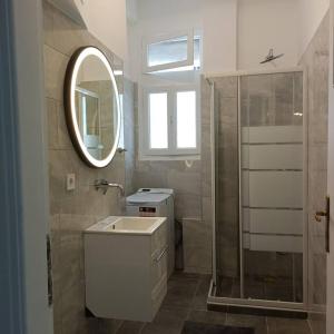 een badkamer met een wastafel, een spiegel en een douche bij GAYA apartments in Athene