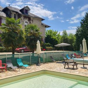 a pool with chairs and umbrellas next to a house at Le Pavillon de St Agnan in Hautefort