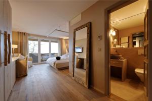 une salle de bains avec un miroir et une chambre avec un lit dans l'établissement Seerose Resort & Spa, à Meisterschwanden