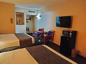 Habitación de hotel con 2 camas, mesa y TV en Metropolitan Inn Downtown Salt Lake City, en Salt Lake City