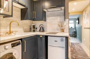 a kitchen with black cabinets and a white dishwasher at The Hideaway by the sea - free parking in Brighton & Hove