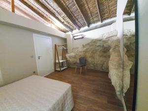1 dormitorio con 1 cama y pared de piedra en Casa rural Abuelo Daniel, en Alcalá del Júcar