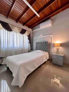 1 dormitorio con cama blanca y ventana en Casa completa, para familia numerosa o eventos. en Medellín