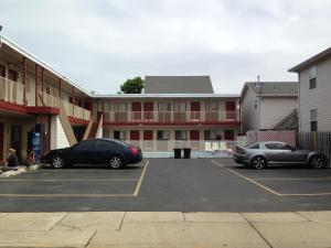 zwei Autos auf einem Parkplatz vor einem Gebäude geparkt in der Unterkunft Flamingo Inn in Seaside Heights