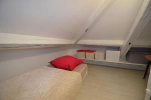 um pequeno quarto com uma cama com uma almofada vermelha em Paris chatou brand new quiet cosy flat em Chatou
