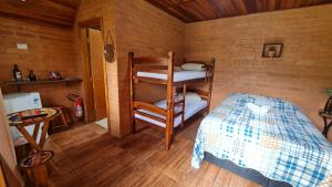 a bedroom with a bunk bed and a chair at Chalés Maranata in São Bento do Sapucaí +30 photos