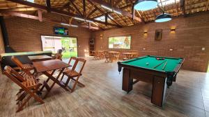 a room with a pool table and tables and chairs at Chalés Maranata in São Bento do Sapucaí