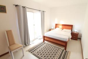 ein Schlafzimmer mit einem Bett, einem Stuhl und einem Fenster in der Unterkunft Quick Stay in Praia #2 in Praia