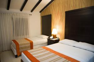 a hotel room with two beds and a lamp at Hotel San Antonio del Cerro in Pereira