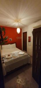 a bedroom with a bed with an orange wall at Pousada Farol do Patacho in Pôrto de Pedras