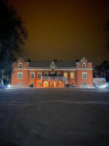 un gran edificio naranja por la noche con sus luces encendidas en Zamek Rynkówka, en Rynkówka