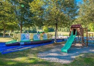 een speeltuin met een groene glijbaan en een speelstructuur bij Oh! Campings - Camping Paradis A l'ombre des tilleuls in Peyrouse