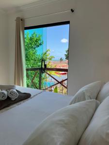 1 dormitorio con cama y ventana grande en Maré Suítes Maragogi, en Maragogi