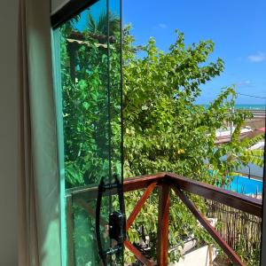balcón con vistas a un árbol y al océano en Maré Suítes Maragogi, en Maragogi