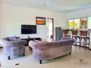 a living room with two couches and a tv at Fiorella Beach House, Diani Beach in Diani Beach