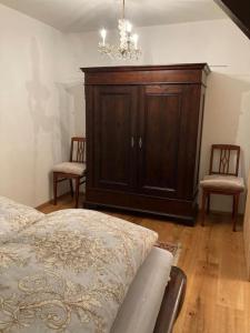 a bedroom with a bed and a cabinet and two chairs at Romantische Ferienwohnung im Grünen in Hohen Neuendorf