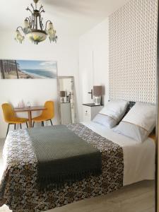 een slaapkamer met een bed, een tafel en een kroonluchter bij Chambre d'hôte Margot'te in Mimizan