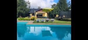 zwei Stühle und ein Sonnenschirm neben einem Swimmingpool in der Unterkunft Casa verano piscina Villarrica in Villarrica