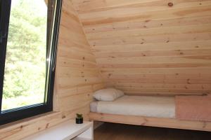 a tiny house with a bed in a room with a window at Między Sosnami in Pasym