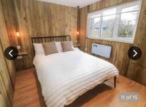 a bedroom with a large bed with wooden walls at Hunting Gate Lodge in Redruth