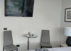 a bedroom with two chairs and a table and a tv at CBD Grampians studio in Nelson
