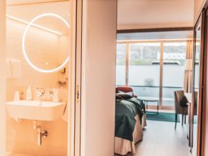a bathroom with a sink and a bedroom at Hotel Ullensvang in Lofthus