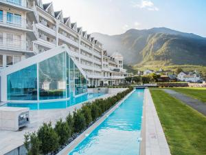 a hotel with a swimming pool in front of a mountain at Hotel Ullensvang in Lofthus